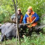 2 men posing with a bull moose